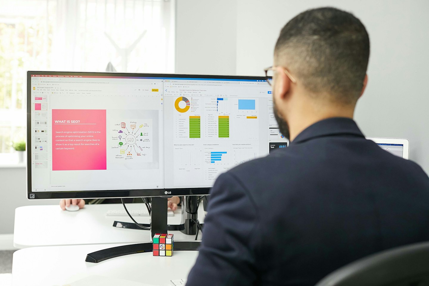 Mężczyzna pracuje przy dwóch monitorach komputerowych wyświetlających SEO i analizy.